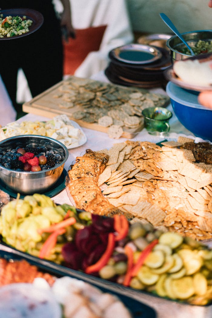 A colorful outdoor buffet table with mixed fruits, crackers, and various dishes, perfect for gatherings.